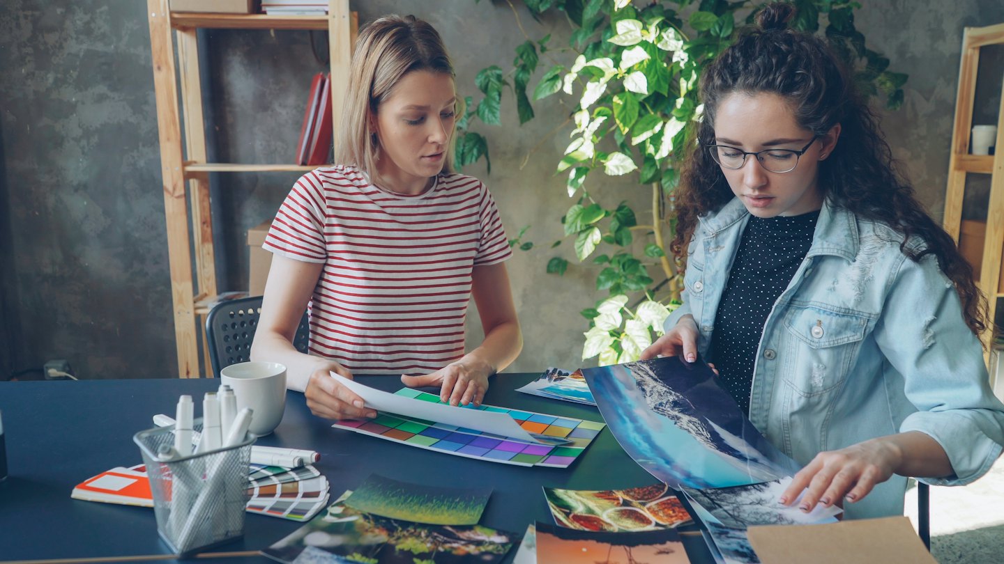 Two women collaborate on a design project with color swatches.