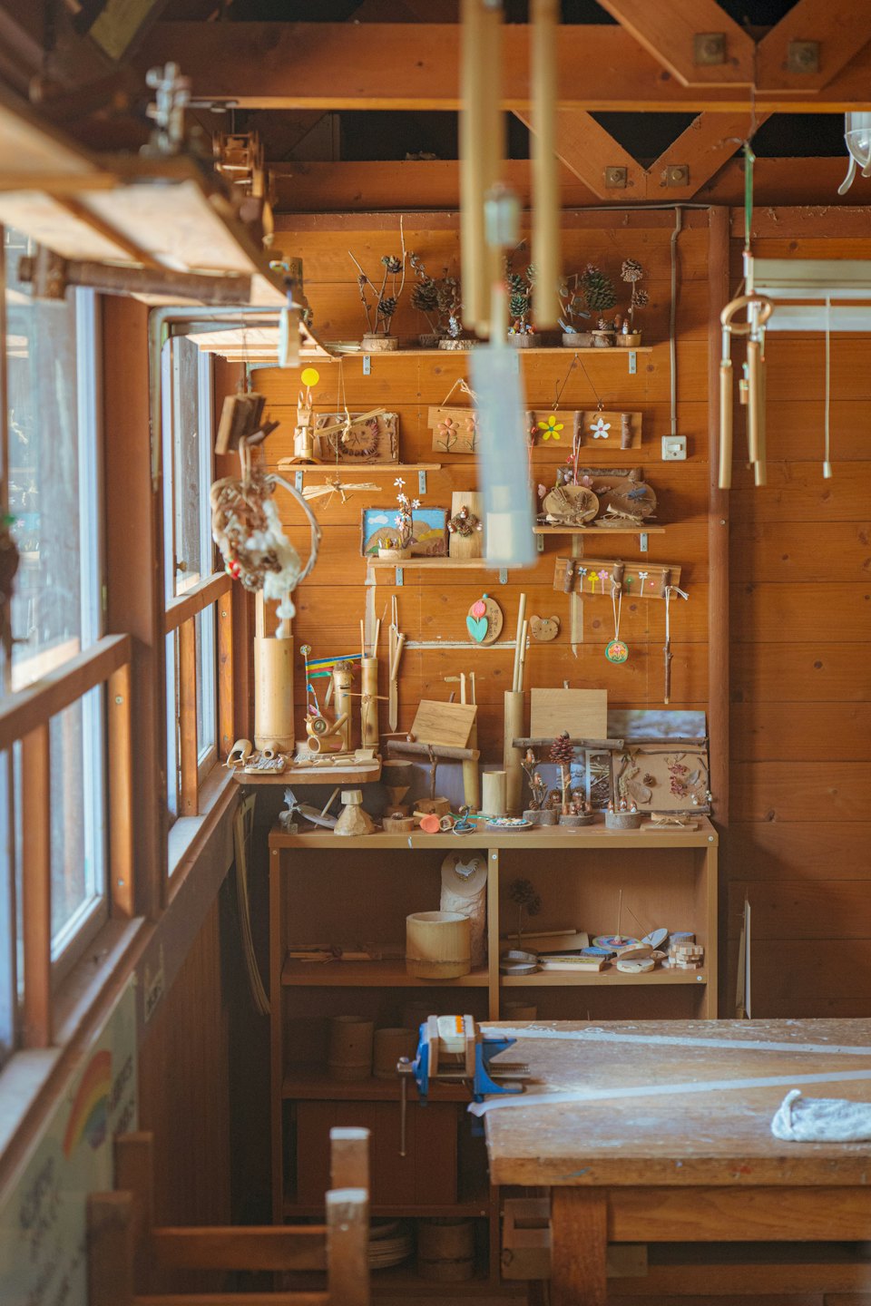 Wooden workbench with tools and handmade crafts on wall.