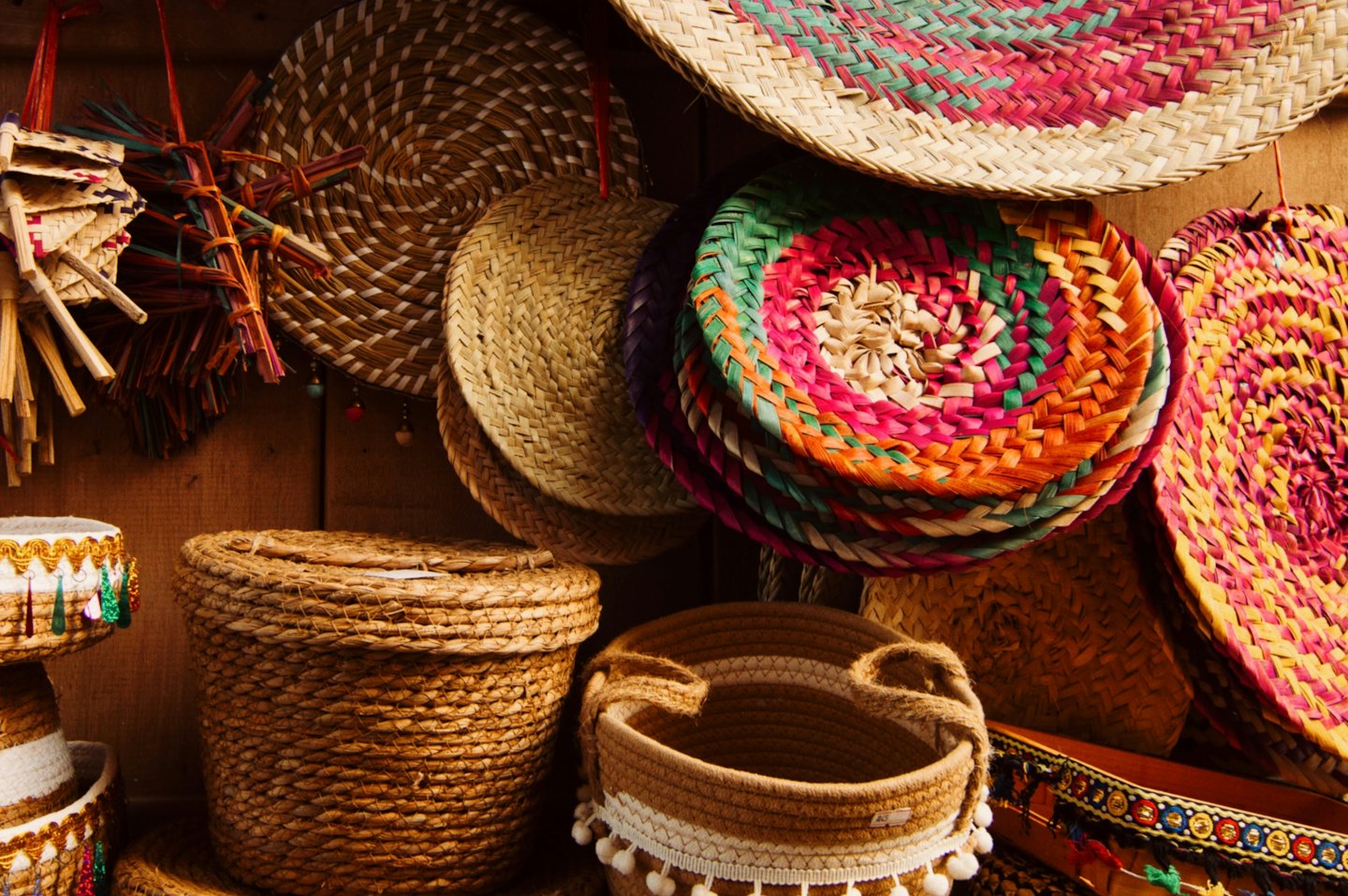 Handcrafted woven baskets and decorative fans displayed on wood.